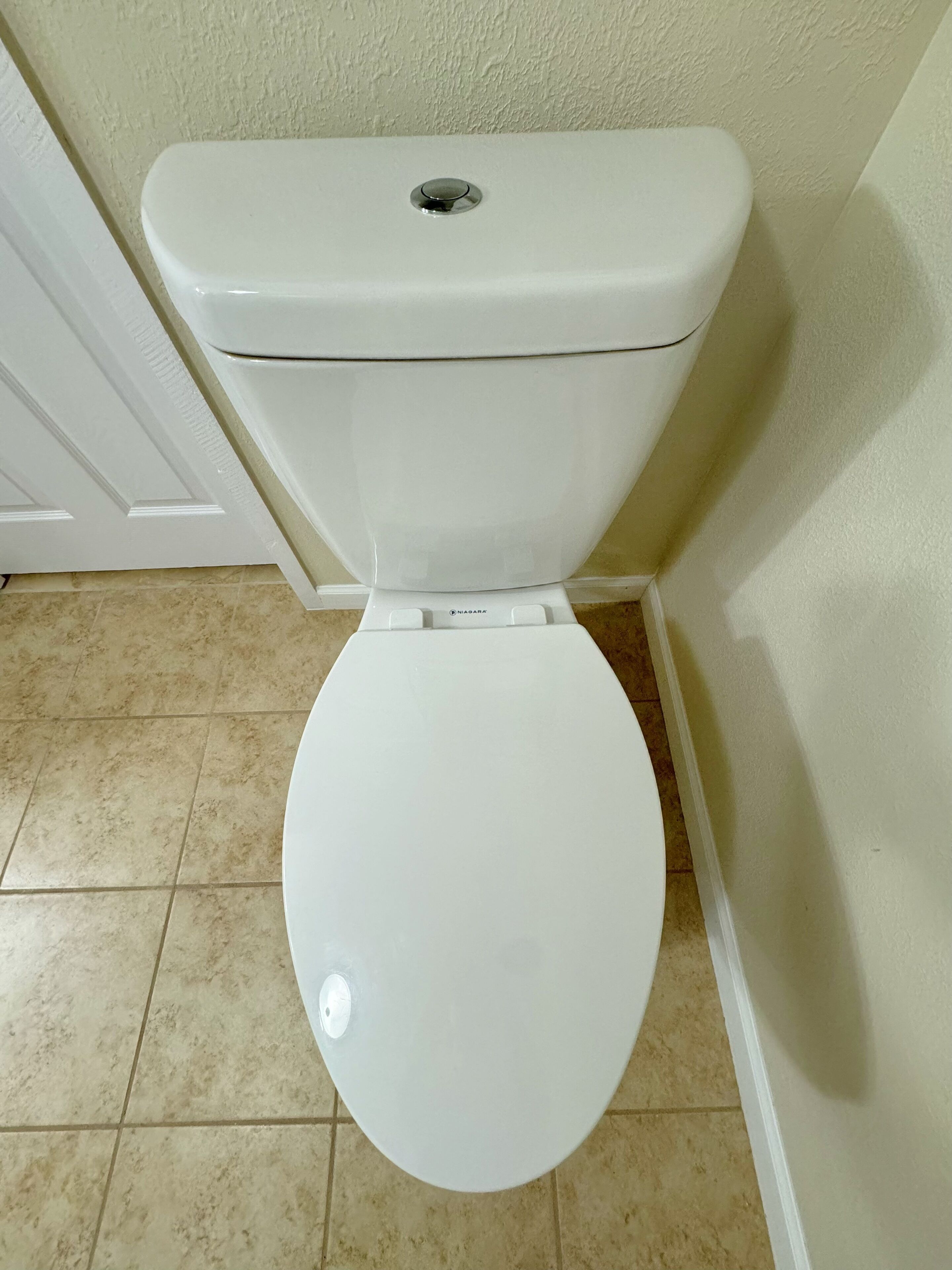 Sanitário branco com tampa fechada, botão de descarga e controle para bidê.