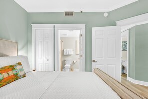 Ein Schlafzimmer mit einem Bett, einem Nachttisch und einer Tür zu einem Badezimmer.