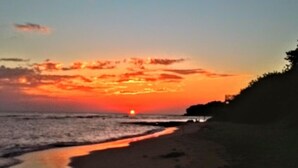 Una playa al atardecer con cielo despejado y mar tranquilo.