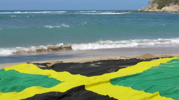 Una playa con olas y una manta colorida al frente.