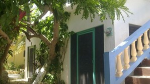 Un edificio con una escalera, una puerta y un árbol.