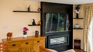 A living room with a wooden cabinet, a black entertainment unit, and a fireplace.