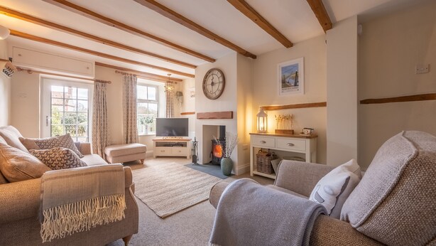 A cozy living room with a fireplace, comfortable seating, and a television. - A delightful mid-terrace Victorian cottage only a short drive from the coast! (Docking)