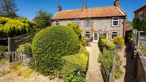 A stone house with a tiled roof, a wooden fence, and a well-maintained garden. - A delightful mid-terrace Victorian cottage only a short drive from the coast! (Docking)