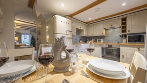 A modern kitchen with white cabinetry, a built-in oven, and a dining area set for a meal. - A delightful mid-terrace Victorian cottage only a short drive from the coast! (Docking)