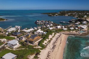 An aerial view of a coastal residential area with houses, a beach, and a marina.
