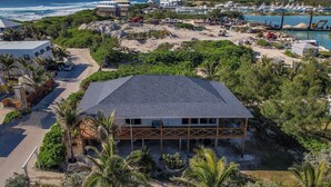 Una propiedad frente a la playa con un edificio grande, una playa de arena y un puerto deportivo al fondo.