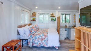 Un dormitorio con cama, mesita de noche y televisor.