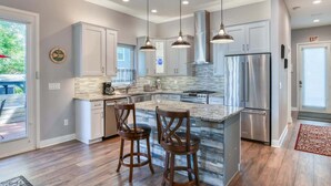 A modern kitchen with a large island, stainless steel appliances, pendant lighting, and a view to the outside. - Big 4 bedroom house walkable to downtown (St Augustine)