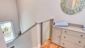 A staircase with a wooden finish, a light-colored wall, and a decorative mirror. - Big 4 bedroom house walkable to downtown (St Augustine)