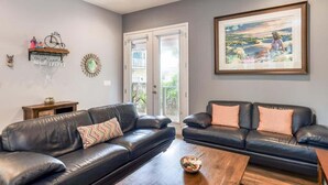 A living room with two black leather sofas, a wooden coffee table, and a framed landscape painting on the wall. - Big 4 bedroom house walkable to downtown (St Augustine)