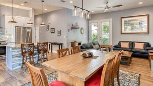 A spacious living area with a wooden dining table, multiple chairs, a black sofa, and a ceiling fan. - Big 4 bedroom house walkable to downtown (St Augustine)