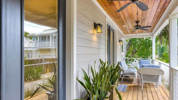 A covered porch with wooden flooring, potted plants, and outdoor furniture. - Big 4 bedroom house walkable to downtown (St Augustine)