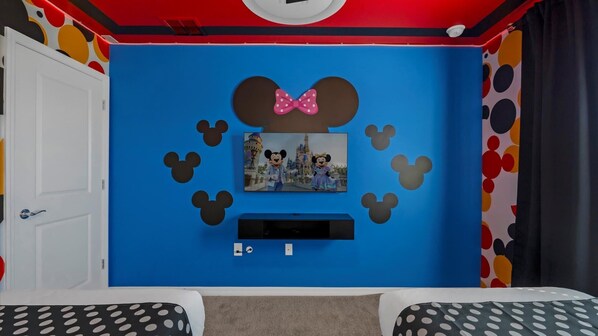 A room with a blue wall, a Mickey Mouse themed TV, and a door.