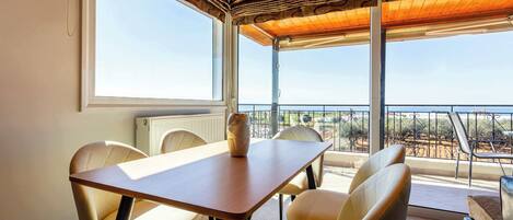 Ein Essbereich mit Holztisch und Stühlen, großen Fenstern und einem Balkon mit Blick.