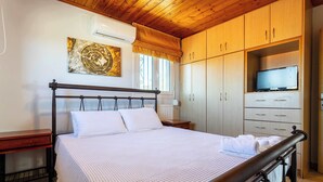 A bedroom with a bed, wooden wardrobe, and a television.