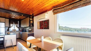 Una cuina moderna amb sostre de fusta, una zona de menjador amb taula i caires, i vista al camp a través d'una finestra.
