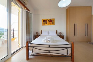 Ein Schlafzimmer mit einem Bett, einer Glastür zum Balkon, einem Holzschrank und einem Bild an der Wand.