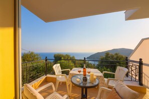 Ein Balkon mit Tisch und Stühlen, der einen schönen Blick auf das Meer und die Hügel bietet.