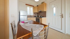 A compact kitchen with wooden cabinets, a stainless steel refrigerator, and a dining table with chairs.
