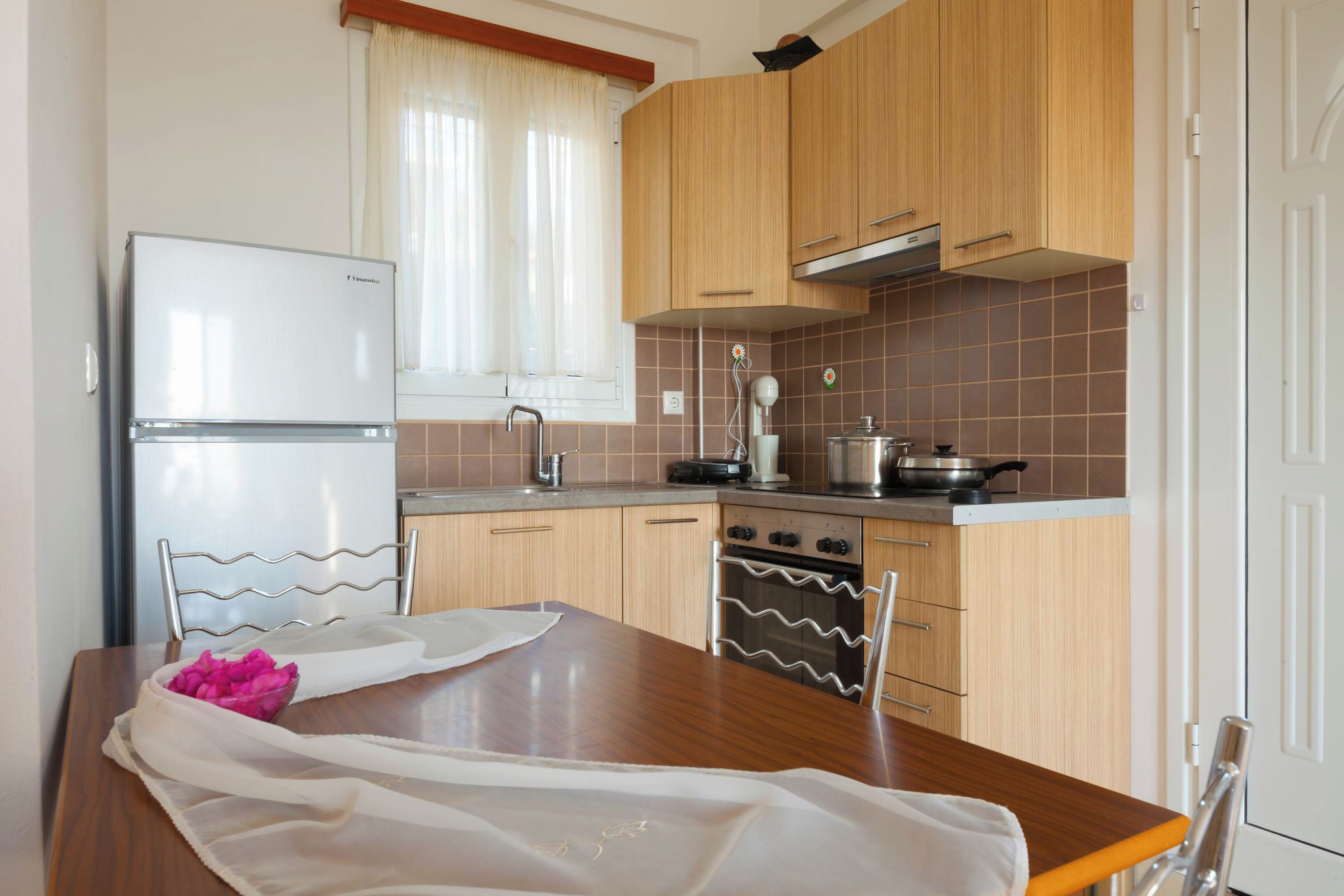 Une cuisine avec des meubles de rangement en bois, une cuisinière, un réfrigérateur et une table à manger avec des chaises.