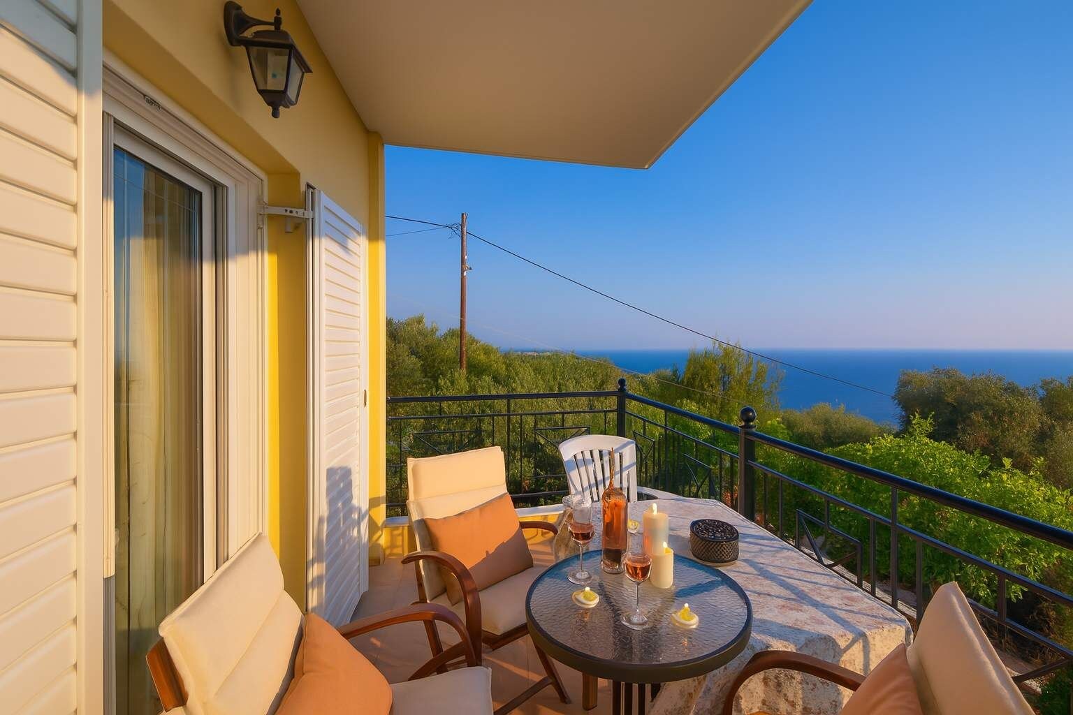 A balcony with a table set for two, overlooking a scenic view of the sea.