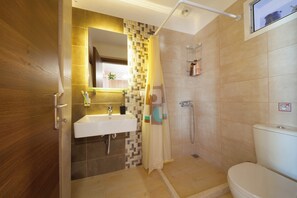 Ein Badezimmer mit Holztür, Waschbecken, Dusche und Toilette.