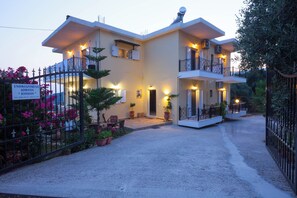 A two-story building with a gated entrance, potted plants, and outdoor seating. - Ionian View Gem - Parga Charming Nest (Agia Kiriaki)