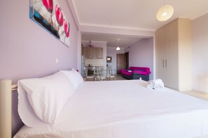 Hotellihuone, jossa on suuri sänky, ruokailutila ja pieni keittiö.