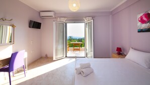 Une chambre à coucher comprenant un lit, un bureau, une chaise, un téléviseur et un balcon avec une table et des chaises.