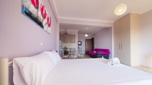 A hotel room with a large bed, a dining area, and a kitchenette. - Ionian View Gem - Parga Ethereal Nest (Agia Kiriaki)