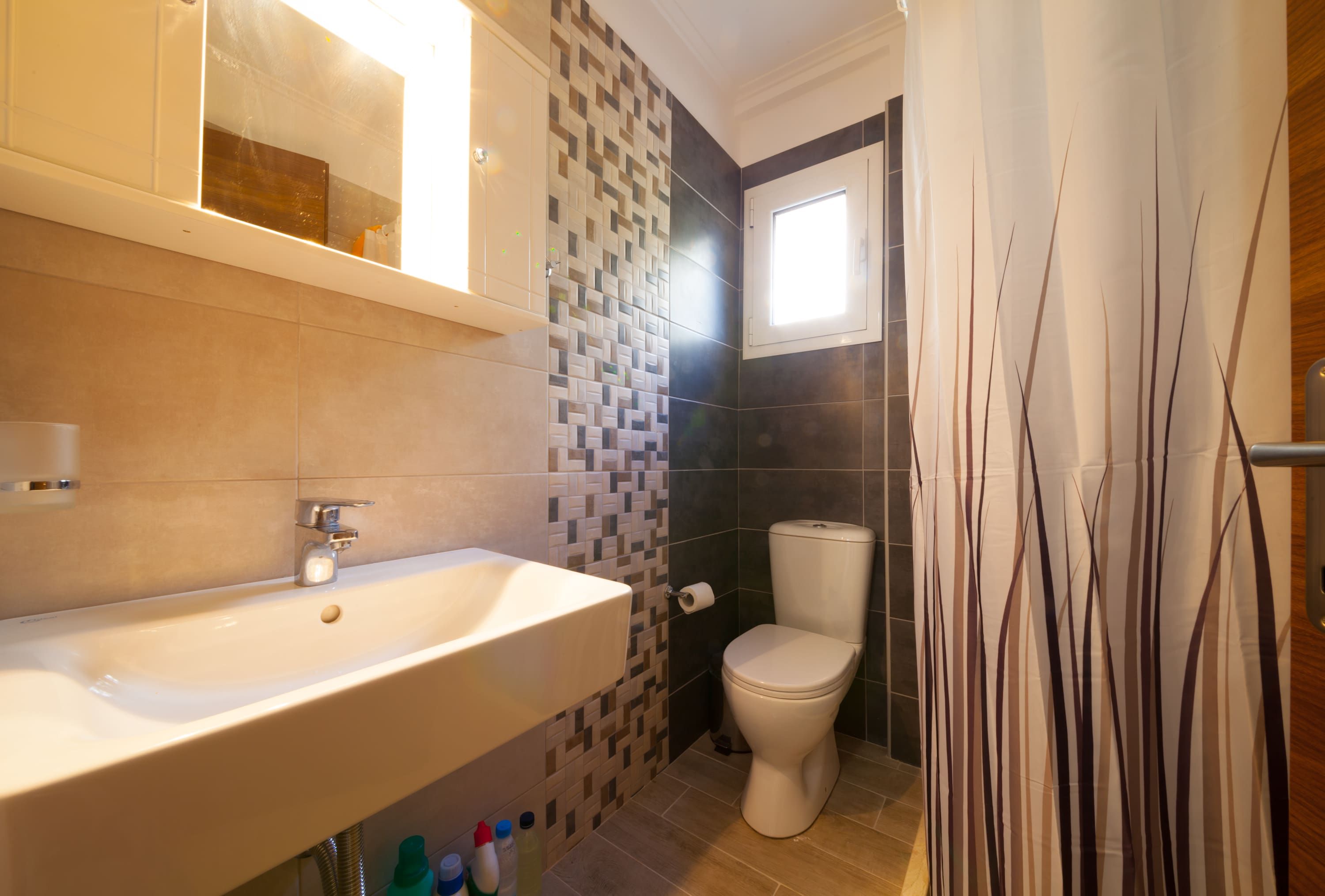 Un baño con lavamanos, inodoro y ventana.