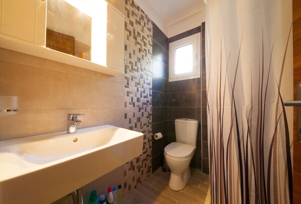A bathroom with a sink, toilet, and a window.