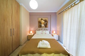 A bedroom with a bed, a painting on the wall, and a nightstand with a lamp.