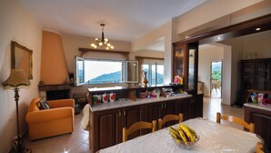 A spacious kitchen with a dining area, a large window with a view, and a chandelier.
