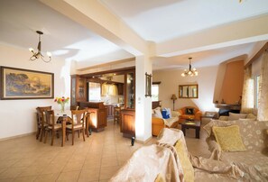 Amplia sala de estar con mesa de comedor, sillas, sofá y cocina al fondo.