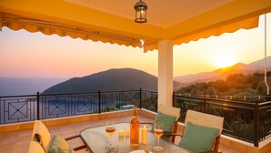 A balcony with a table set for two, a bottle, glasses, and candles.