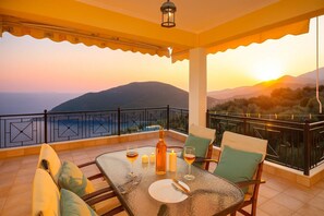A balcony with a table set for two, a bottle, glasses, and candles. - Ionian View Haven - Parga Panoramic Seaview (Agia Kiriaki)