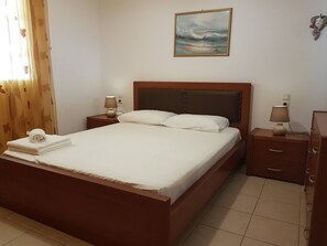 Una cama bien hecha con sábanas blancas, un cabecero de madera y dos mesitas de noche con lámparas.