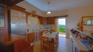 A spacious kitchen with wooden cabinets, a central island, and a view of greenery through the sliding glass door.