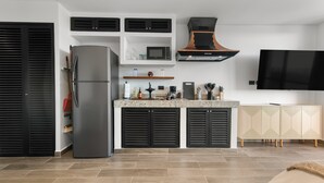 A modern kitchen with a built-in microwave, a stainless steel refrigerator, and a black range hood.