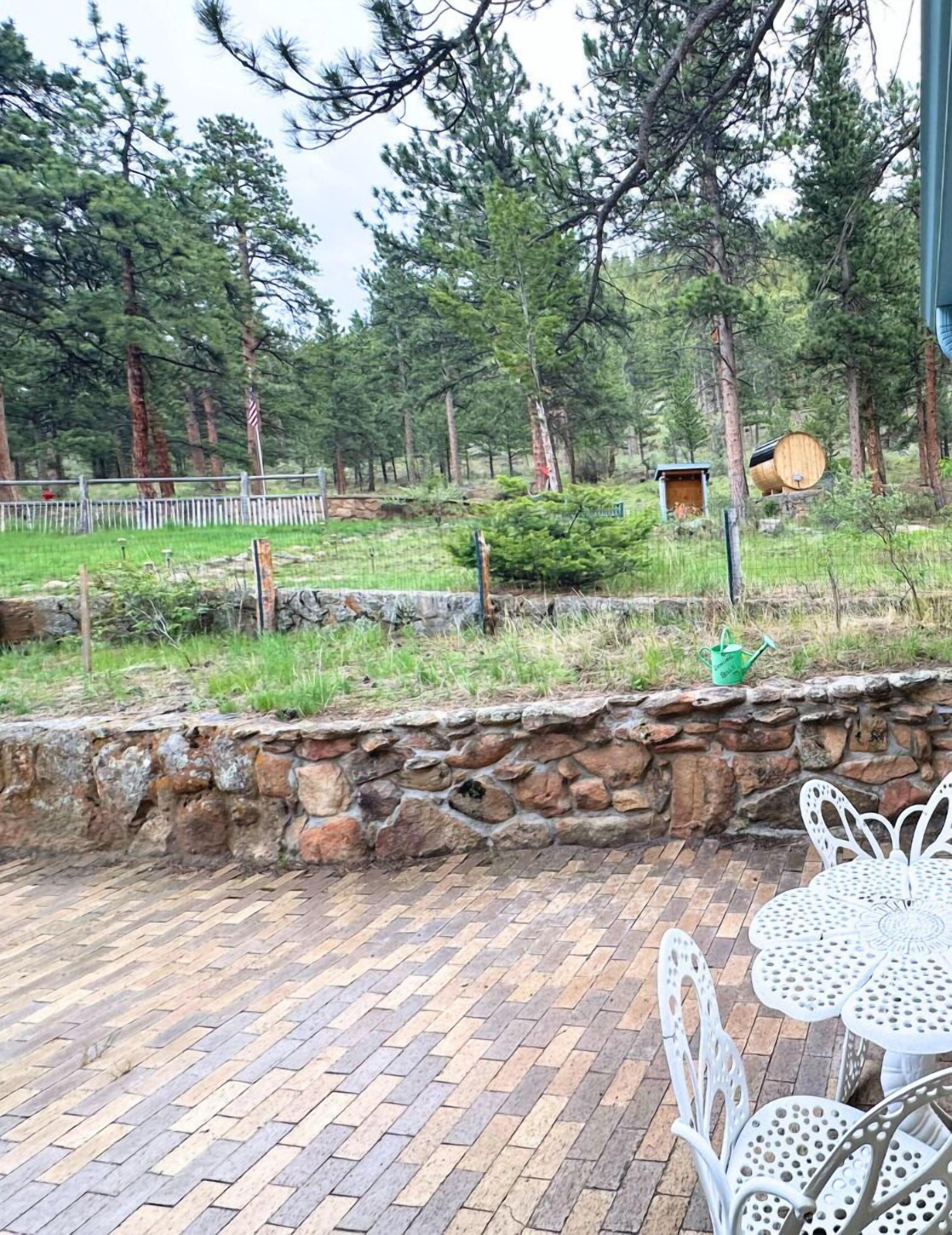 A patio area with stone walls, a wooden barrel, and a birdhouse.