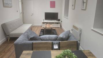 Una sala de estar moderna con sofá, una mesa de centro y televisor.