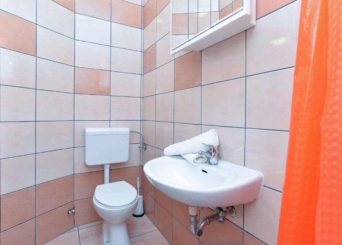 A bathroom with a toilet, sink, and tiled walls.