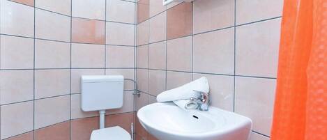 A bathroom with a toilet, sink, and tiled walls.