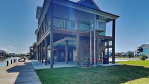 A modern two-story building with a covered outdoor area, a dock, and a grassy lawn.