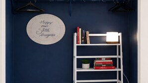 Habitació amb parets de blau fosc, una estanteria blanca plena de llibres i un globus, dos otomans beix i una placa rodona amb un missatge.