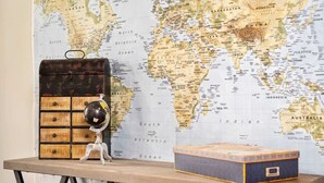 Une table en bois, sur laquelle sont posés un globe terrestre et une boîte de rangement, le tout sur fond d’une carte du monde.
