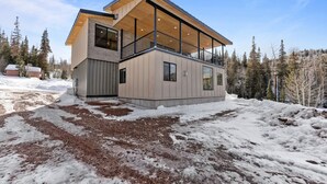 A modern cabin with a large balcony, a wooden deck, and a view of a snowy forest. - Summer Getaway | Pool Table, Foosball & Views (Brian Head)