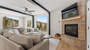 A modern living room with a fireplace, large windows, and a cozy sofa. - Summer Getaway | Pool Table, Foosball & Views (Brian Head)